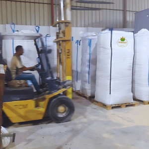 Forklift in warehouse with large bags.